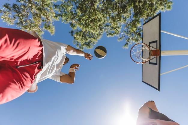 Free photo low angle view of basketball player throwing ball against blue sky
